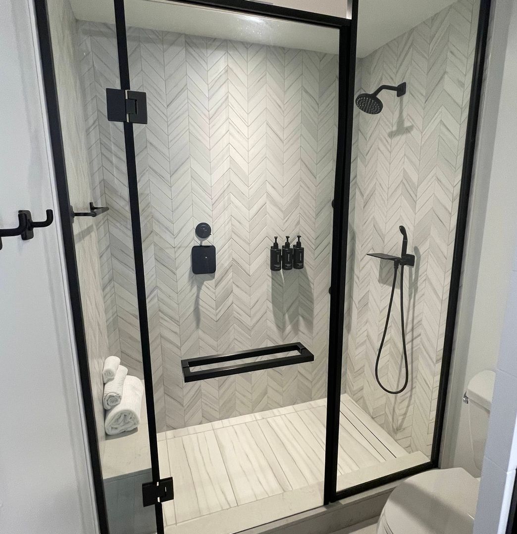 fully romodeled master glass shower with black trim and fixtures and white tile