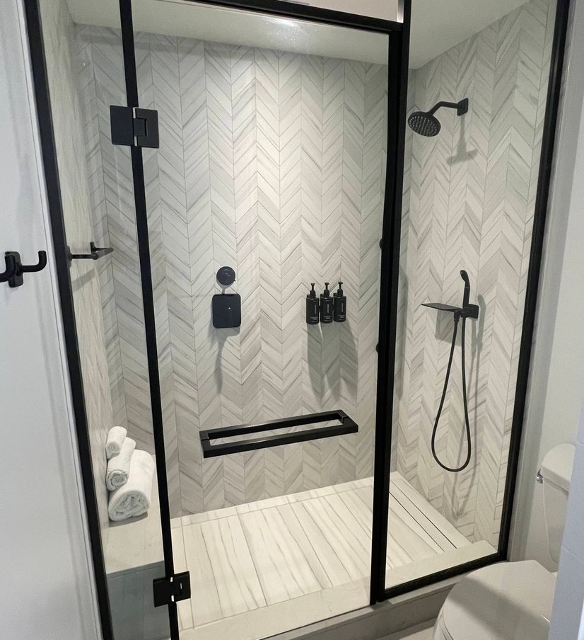 modern and clean remodeled shower with glass doors and white tile